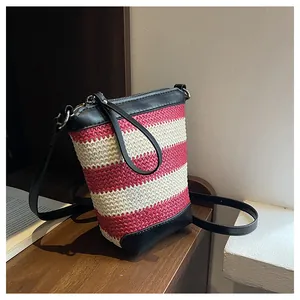 Detail of red and white woven bucket bag with black leather trim and zipper closure