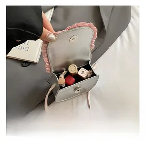 Open view of silver mini crossbody bag showing internal storage for lipsticks and small items