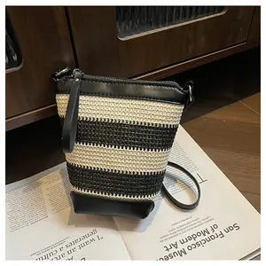 Detail of black and white striped woven bucket bag with leather strap and silver hardware