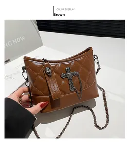 Detail of brown quilted shoulder bag with metal cross and skull charms for women