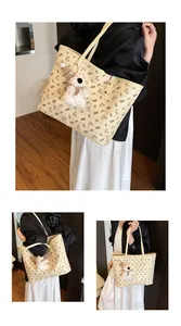 Detailed close-up of beige tote bag with cartoon bear prints and plush charm accessory