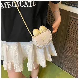 Detailed view of mini cream crossbody bag with large bow and lace trim on a model