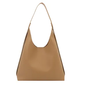 Brown leather tote bag with shoulder strap and integrated handle on a white background