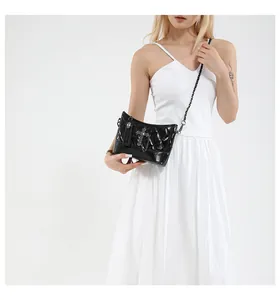 Detailed macro view of black quilted crossbody bag with skull charm and chain strap