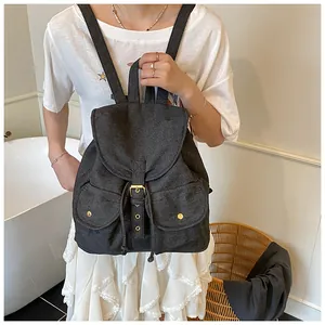 Detail of black denim backpack featuring classic flap closure and dual side patch pockets
