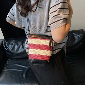 Fashionable red and beige woven bucket bag with black leather strap on a model