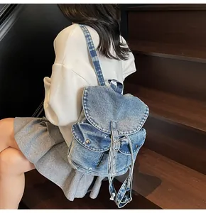 Detalle de mochila vintage de mezclilla lavada con solapa y hebillas metálicas de moda