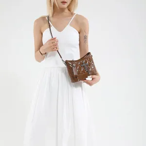 Brown quilted leather crossbody bag with silver cross charm and slim shoulder strap