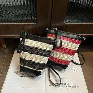Stylish woven bucket bag in black and red stripes with leather straps on a magazine