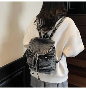 Detalle macro de mochila de mezclilla con cierre de cordón y bolsillos frontales con solapa