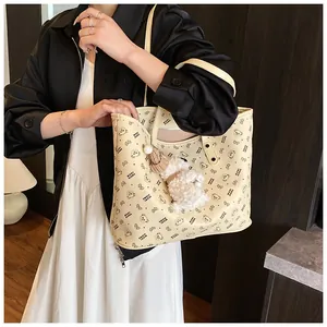 Detail of cream tote bag with bear print and plush charm decoration in daily use