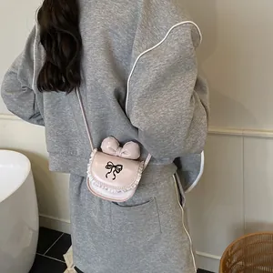 Kids mini pink crossbody bag with 3D bow and white lace trim shown on a model