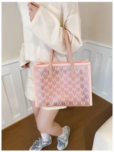 Close-up of pink translucent jelly tote bag with letter M print and leather handles