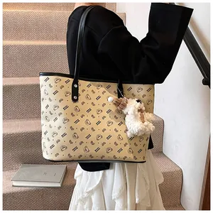 Detail of beige tote bag with black bear prints and a plush bear keychain accessory