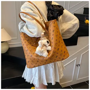 Close-up of a brown tote bag with cartoon bear prints and a white plush puppy keychain