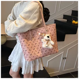 Detail of pink tote bag with bear pattern, long shoulder straps and plush charm
