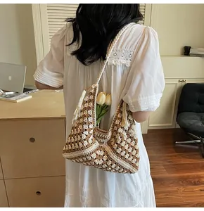 Detail of hand-crocheted tote bag with hollow flower patterns and side tassel decor