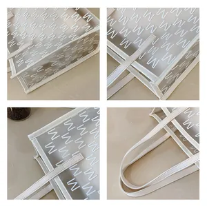 Detail of transparent PVC tote bag featuring white letter prints and reinforced cream stitching
