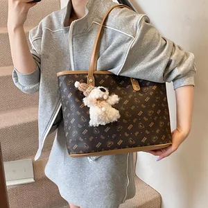 Large dark brown tote bag with bear print and plush charm shown on female model