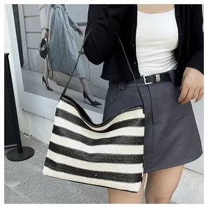 Détail du grand sac de plage en paille à rayures noires et blanches avec bandoulière fine