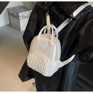 Detailed view of white quilted mini backpack with mesh trim and metal brand plate