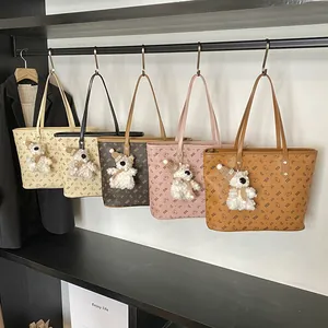 Large capacity Komi Bear tote bags in five colors with cute bear charms on a rack