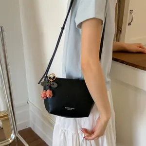 Minimalist black half-moon crossbody bag with cherry charm shown on a fashion model