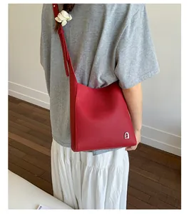 Détail du sac à épaule en cuir rouge avec texture grainée et logo argenté sur le mannequin