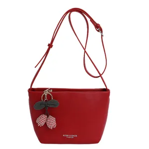 Minimalist red faux leather crossbody bag with cherry charm and logo detail