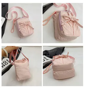Detailweergave van een roze crossbody telefoontasje met strik en dubbele ritsen