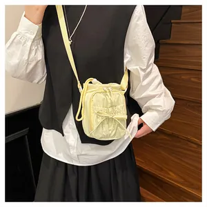 Detail van lichtgele crossbodytas met strikaccent en nylon textuur op houten trap