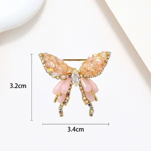 Detail shot of a golden butterfly brooch with pink crystals measuring 3.4cm by 3.2cm