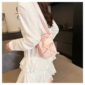 Detail van roze nylon mini crossbody tas met een strikje en trekkoordsluiting