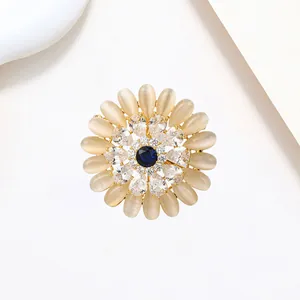 Macro view of sunflower brooch featuring yellow cat eye stones and a deep blue gemstone