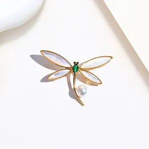 Detail of dragonfly brooch with golden wings, green gemstone and white pearl