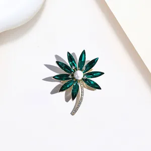 Detail of flower brooch with dark green crystal petals and central white pearl accent
