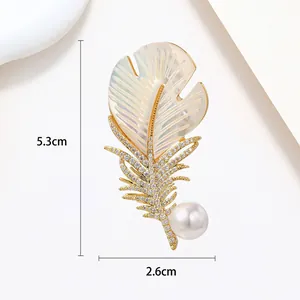 Detail shot of feather brooch with size markers 5.3cm x 2.6cm and pearl accent