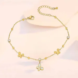 Close-up of golden butterfly anklet with shell charms and sparkling zircon accents