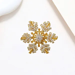 Close-up of snowflake brooch with yellow and white zircon stones on gold metal