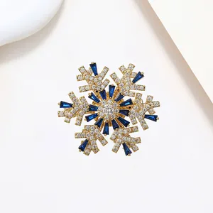 Detailed macro view of rotating snowflake brooch with blue crystals and gold plating