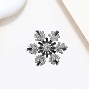 Macro detail of rotating snowflake brooch with inlaid crystals and silver-tone finish