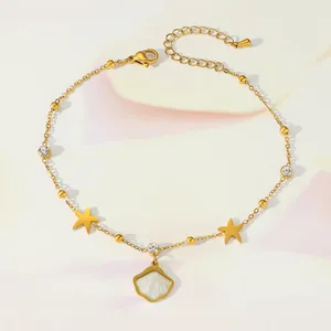 Detail of gold butterfly anklet with sparkling zircon stars and pearl shell charm