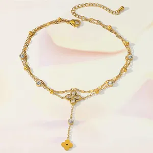 Close-up of golden double-layer anklet featuring zircon stones and clover pendants