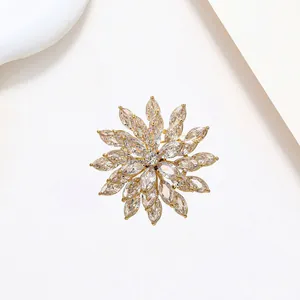 Macro shot of layered gold snowflake brooch with zircon crystal petals on white background