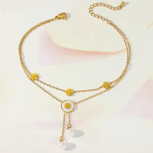 Close-up of double-layer gold anklet with four-leaf clover charms and pearl pendants