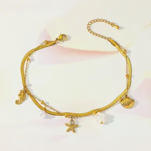 Detailed macro of gold layered anklet featuring seahorse and starfish charms with pearls