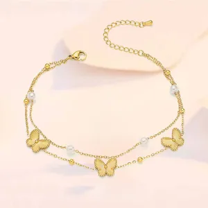 Detail of gold butterfly anklet featuring double-layer chains and white pearl accents