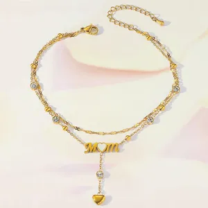 Detail of gold MOM ankle bracelet featuring zirconia charms and double chain design