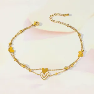 Detail of gold layered anklet with heart pendants, white enamel and zircon accents