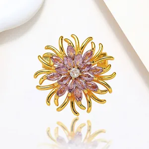 Macro shot of spinning flower brooch with purple zircon petals and golden metal finish